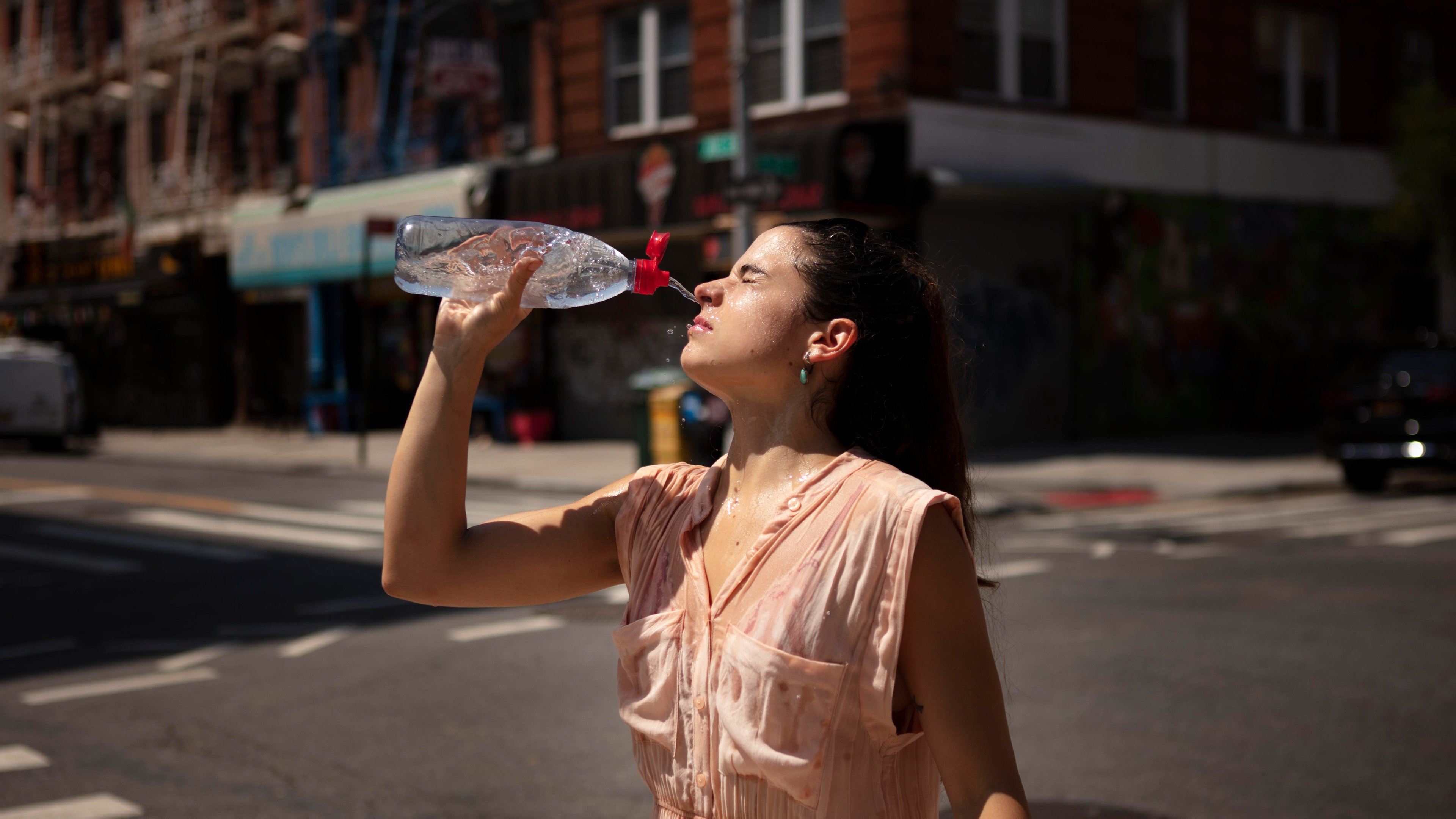 Mulher combate calor na cidade borrifando água sobre o próprio rosto